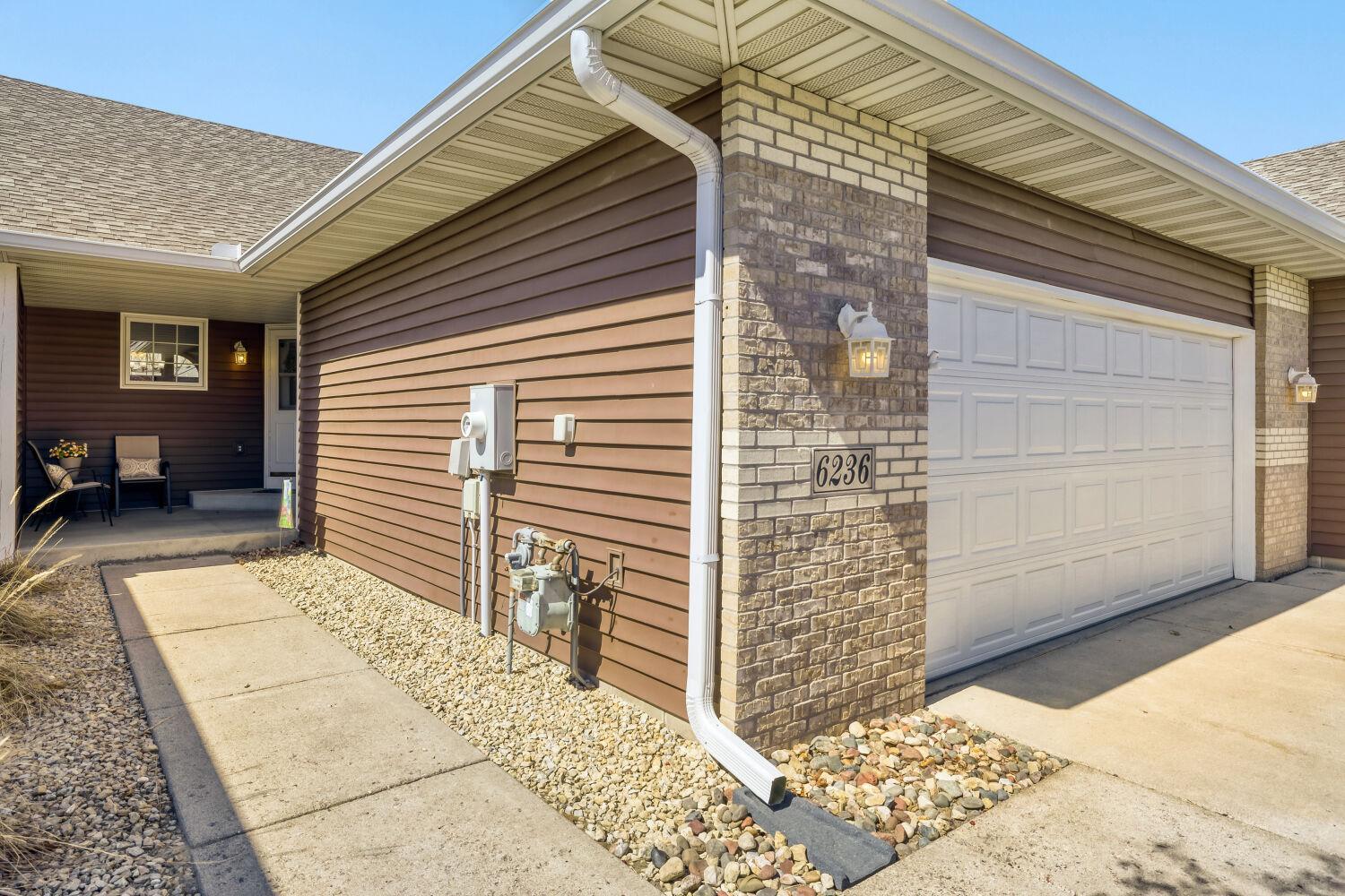 Front entrance showing how the sidewalk wraps around the garage and leads to the entrance. The roof was replaced in 2022 along with some of the windows.