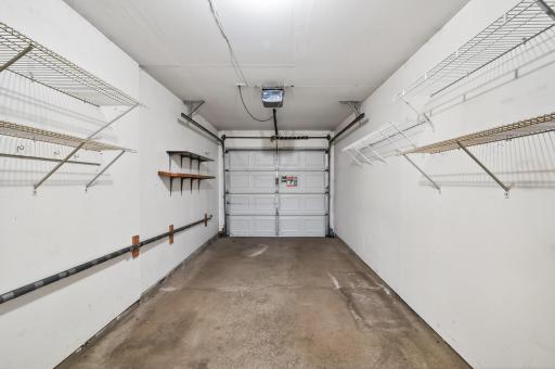 On car garage with lots of shelving and garage door opener.