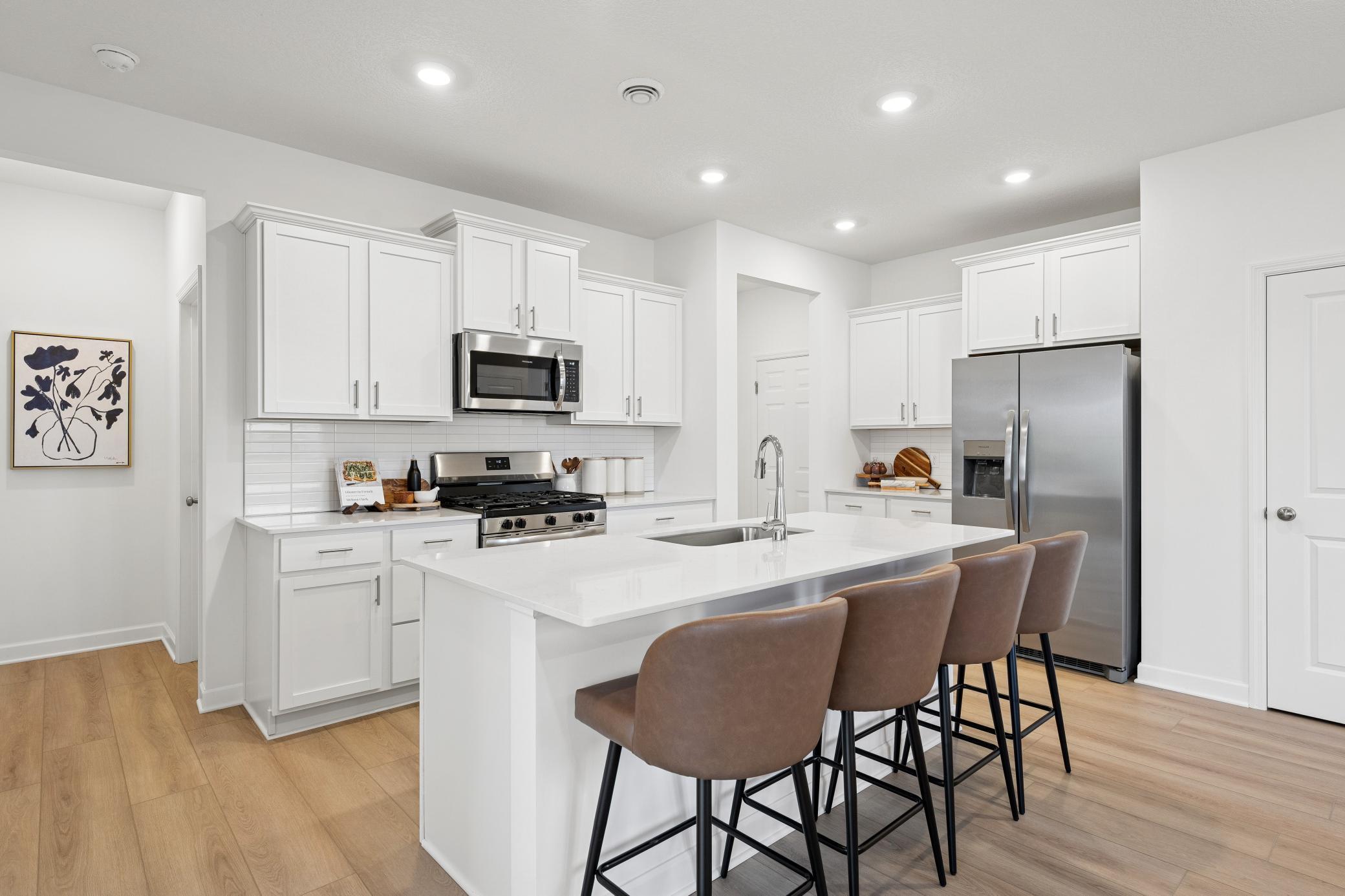 (Photo of a decorated model, actual homes finishes will vary) The multifunctional kitchen is equipped with brand-new stainless steel appliances, ample cabinetry storage, and a center island that doubles as a breakfast bar.