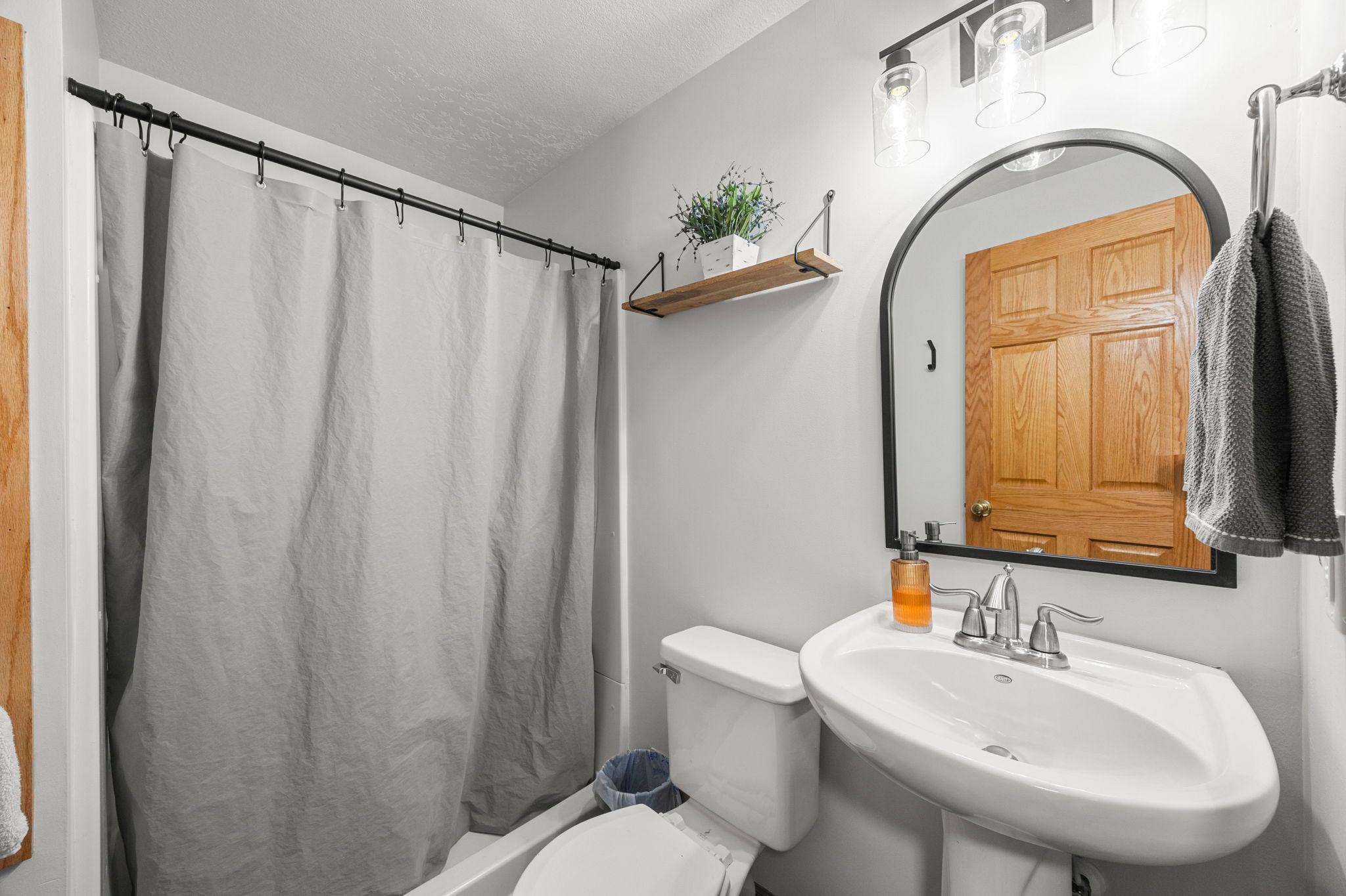A ¾ bathroom offers tile flooring, a walk-in shower, and built-in shelving for decor and storage.