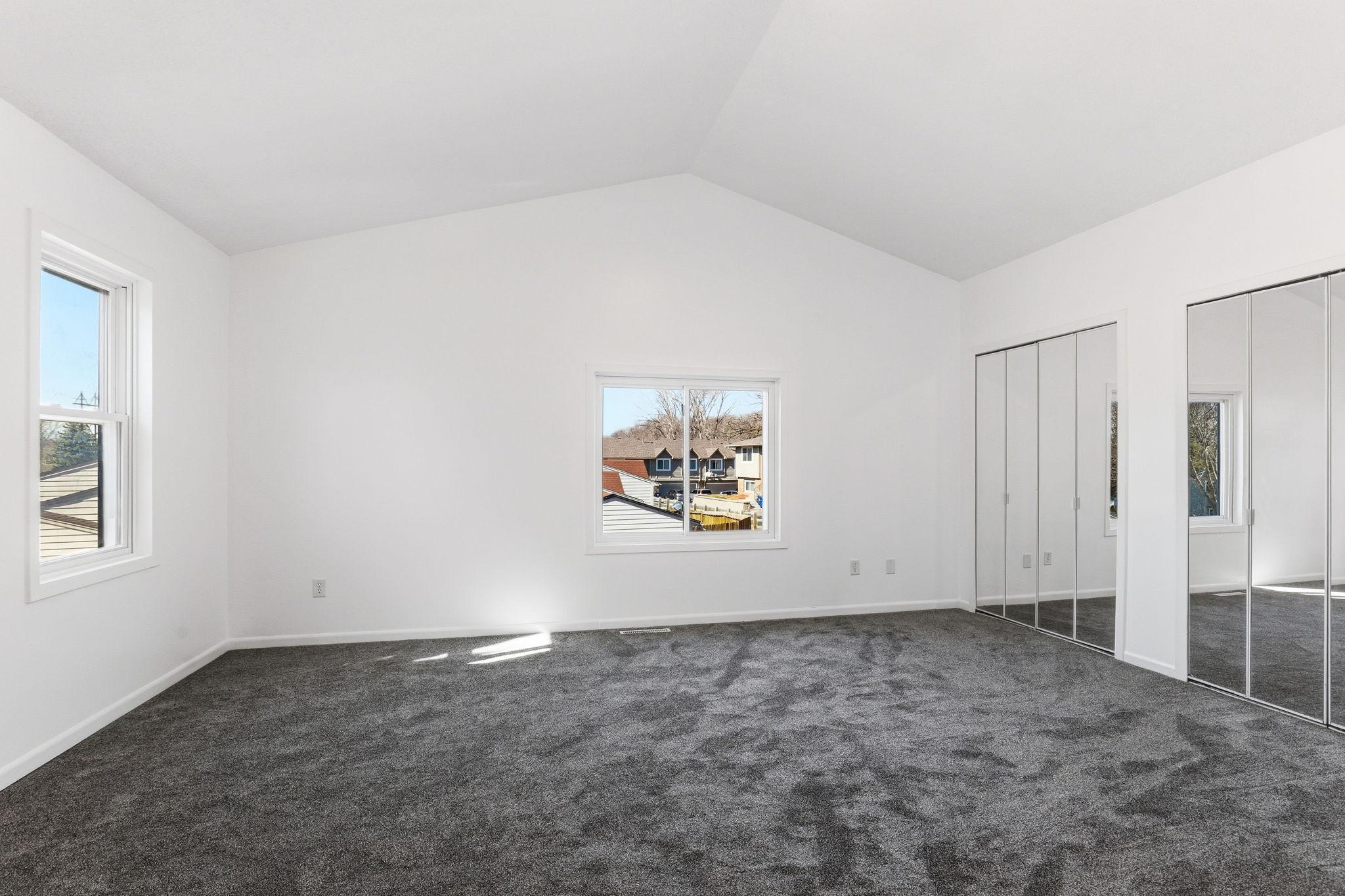 Spacious primary bedroom featuring multiple windows that fill the room with natural light