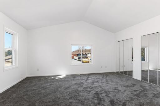 Spacious primary bedroom featuring multiple windows that fill the room with natural light