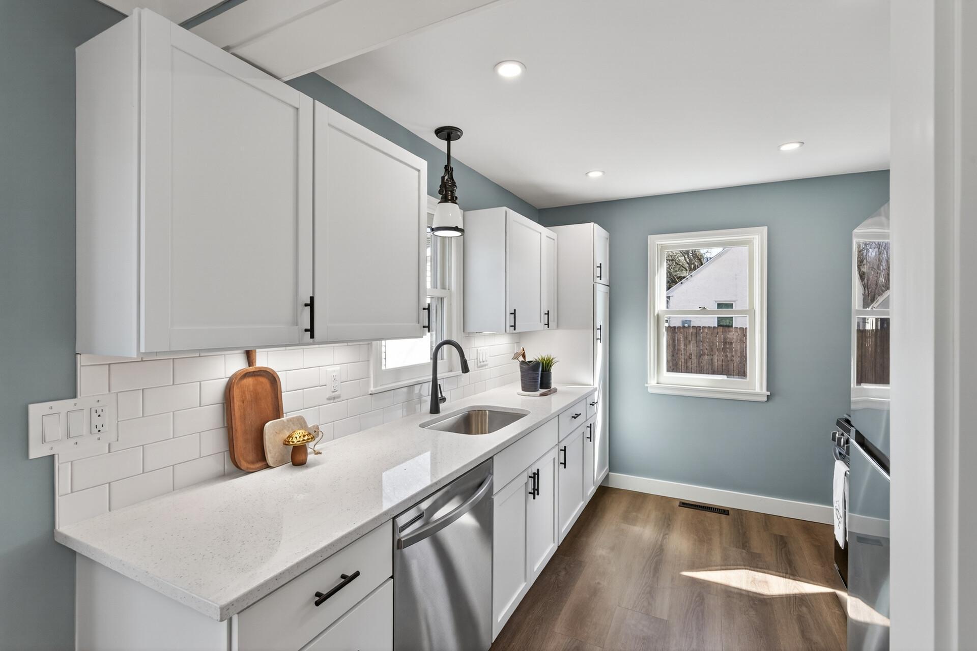 The beautifully updated kitchen showcases crisp white cabinetry, quartz countertops, a stylish tile backsplash, and LVP flooring.
