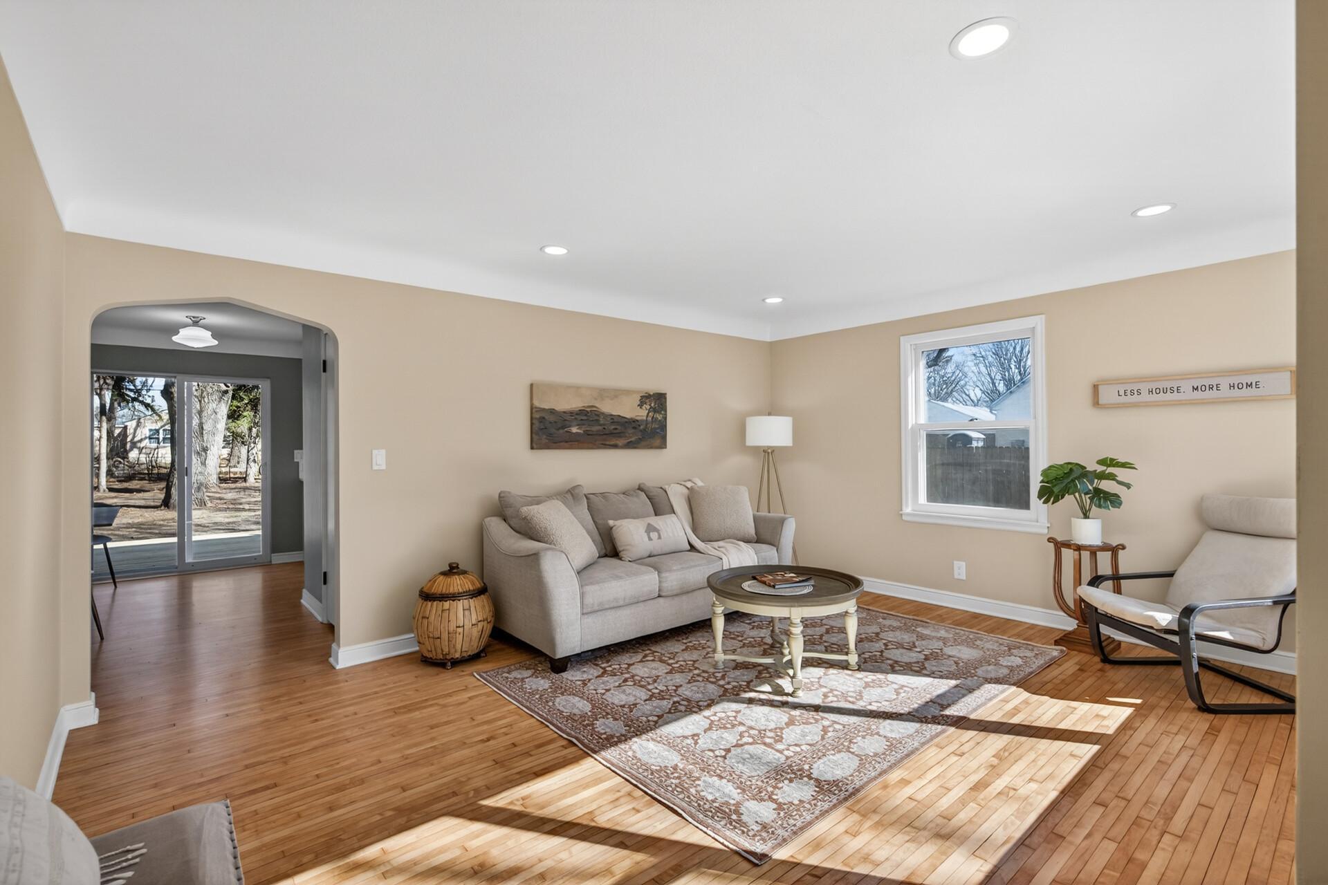 As you enter, the living room features neutral tones, abundant natural light, and refinished maple hardwood floors that flow throughout.