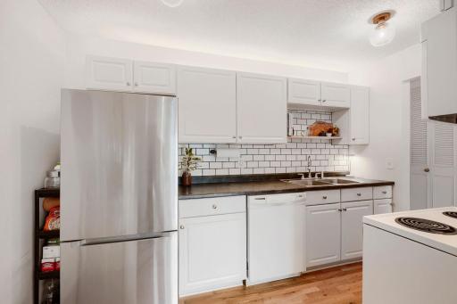 Updated galley style kitchen with dishwasher, new refrigerator and kitchen tile backsplash