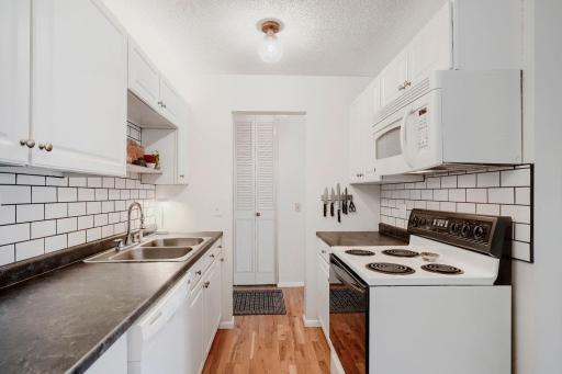 Updated galley style kitchen with dishwasher, new refrigerator and kitchen tile backsplash