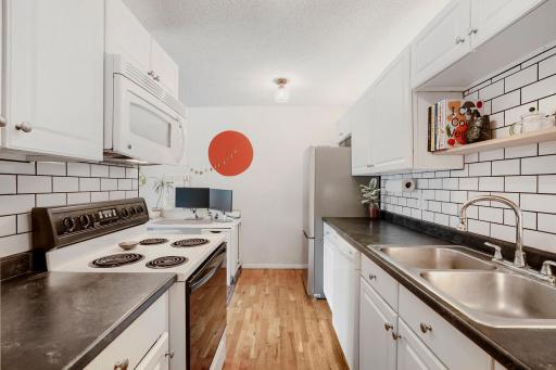 Updated galley style kitchen with dishwasher, new refrigerator and kitchen tile backsplash