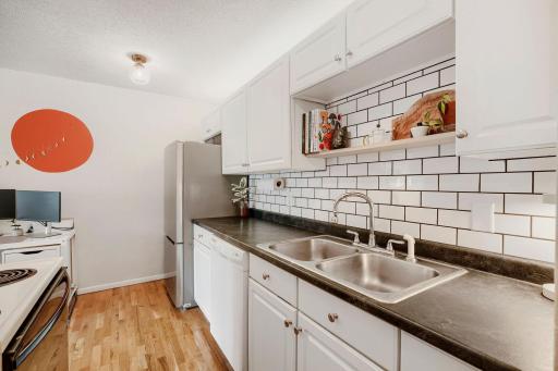 Updated galley style kitchen with dishwasher, new refrigerator and kitchen tile backsplash