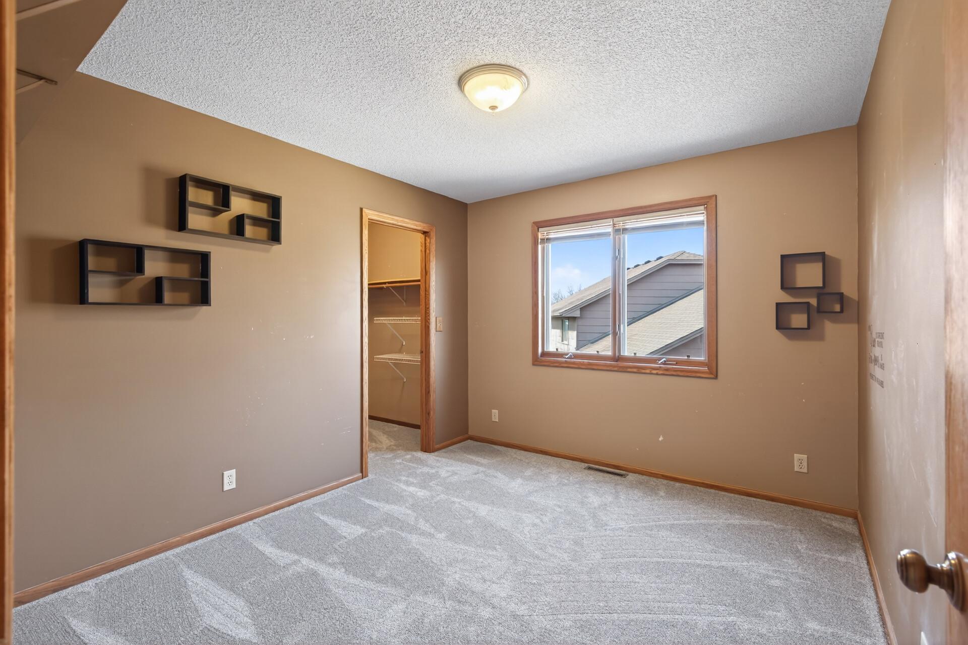 Second upper level bedroom with neutral tones, plush carpeting, and abundant natural light.
