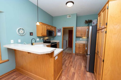 The kitchen boasts rich wooden cabinetry, hard surface floors, and sleek stainless steel appliances.