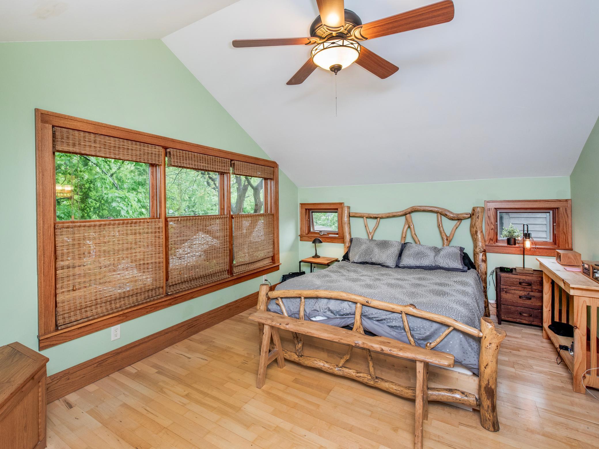 Large primary bedroom with hardwood flooring and vaulted ceiling.