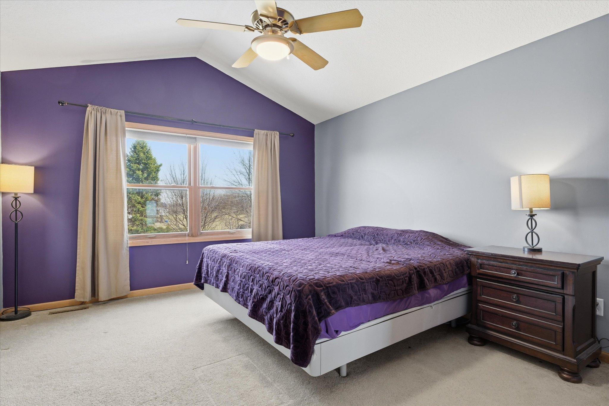 Spacious Primary suite with vaulted ceiling and large windows looking out to backyard.