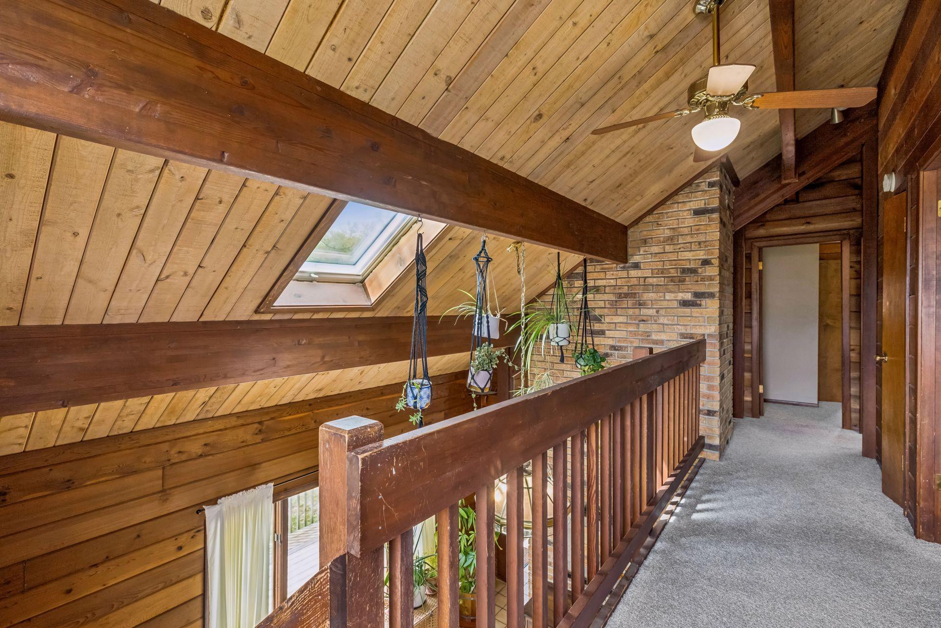 Open wood staircase leads to a loft style hallway overlooking the dining room. Note the skylight!