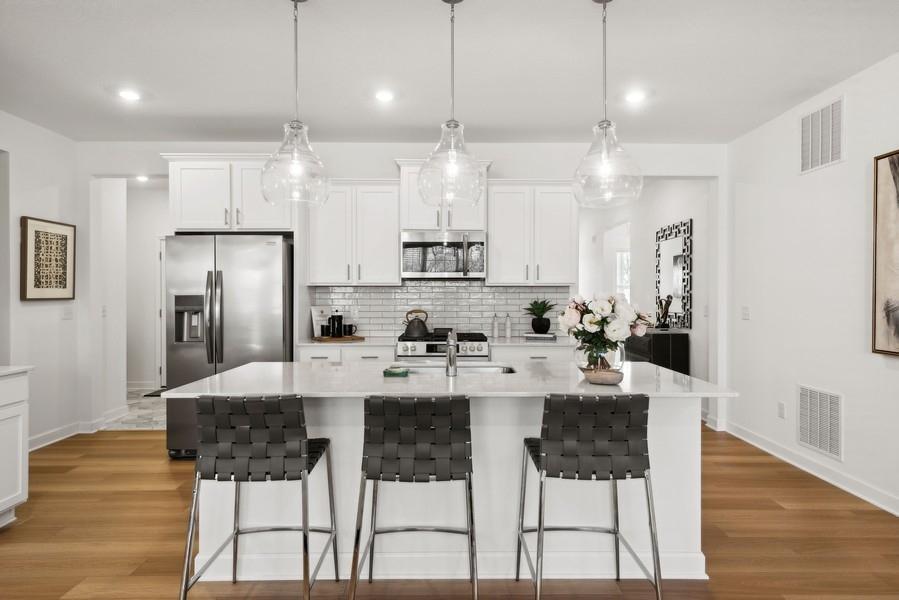 (Photo of a decorated model, actual homes finishes will vary) The spacious kitchen feature a large center island, quartz countertops, LVP floors, stainless appliances and more!