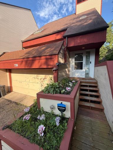 Exterior: Welcoming front entry with raised garden planters, wood steps, and an attached garage, creating a charming and secure first impression.