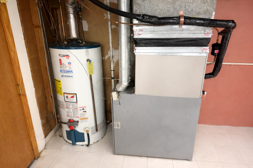 A compact utility area houses a gas water heater and furnace with exposed ductwork and piping, arranged efficiently along tiled flooring for easy access and maintenance.