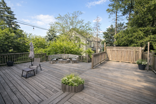 Expansive multi-level deck professionally cleaned to highlight its natural wood character, open entertaining areas, and central round planter surrounded by mature trees.