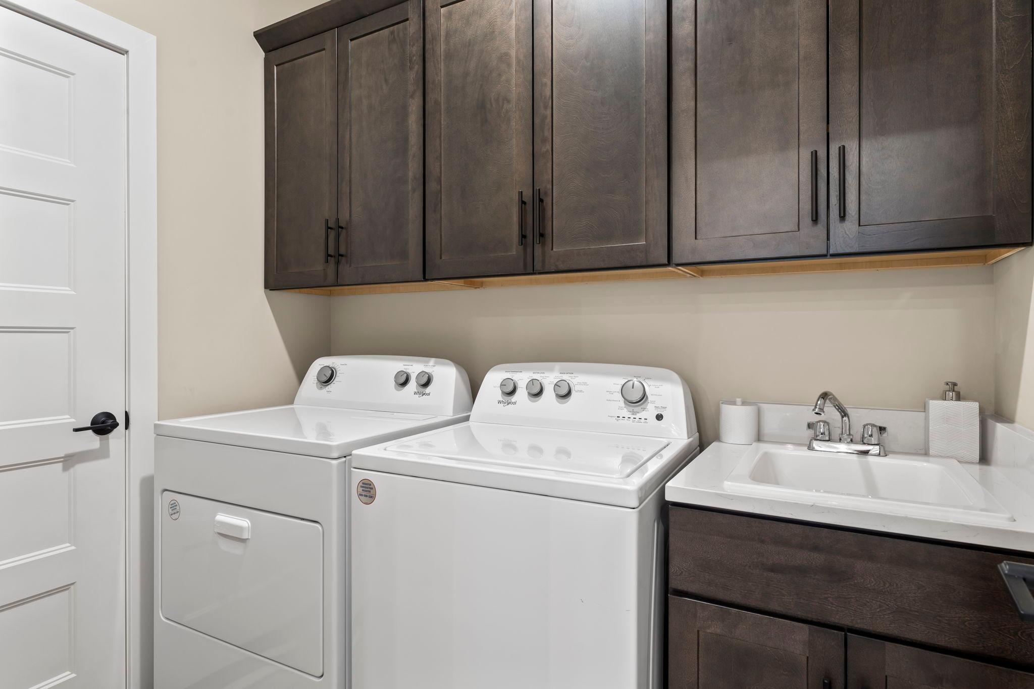 All homes have a deep utility sink and one upper cabinet in the laundry room. This home has upgraded wall to wall cabinets for amazing storage space. The door to the left is the mechanical room.