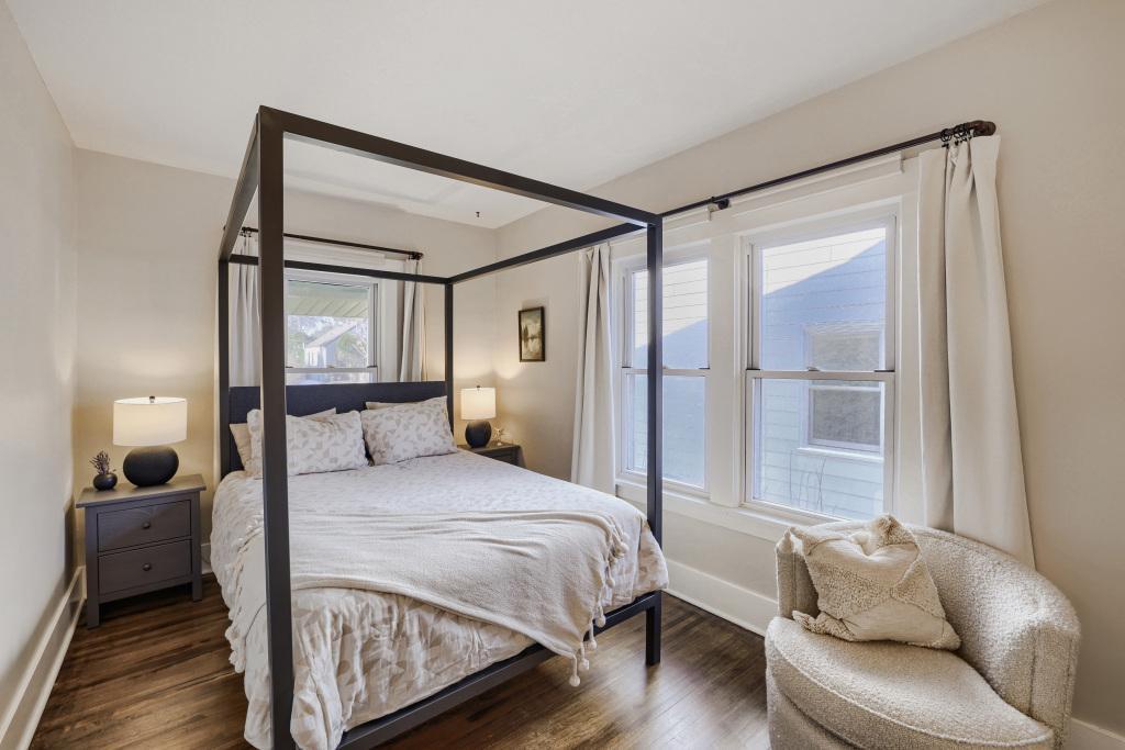 The primary bedroom offers plenty of light through multiple large windows that function well. Note the hardwood floors here as well.
