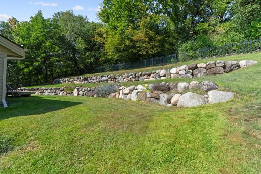 Tiered boulder walls add beautiful dimension to the landscape, while the fully fenced yard keeps the entire outdoor space enclosed and functional.