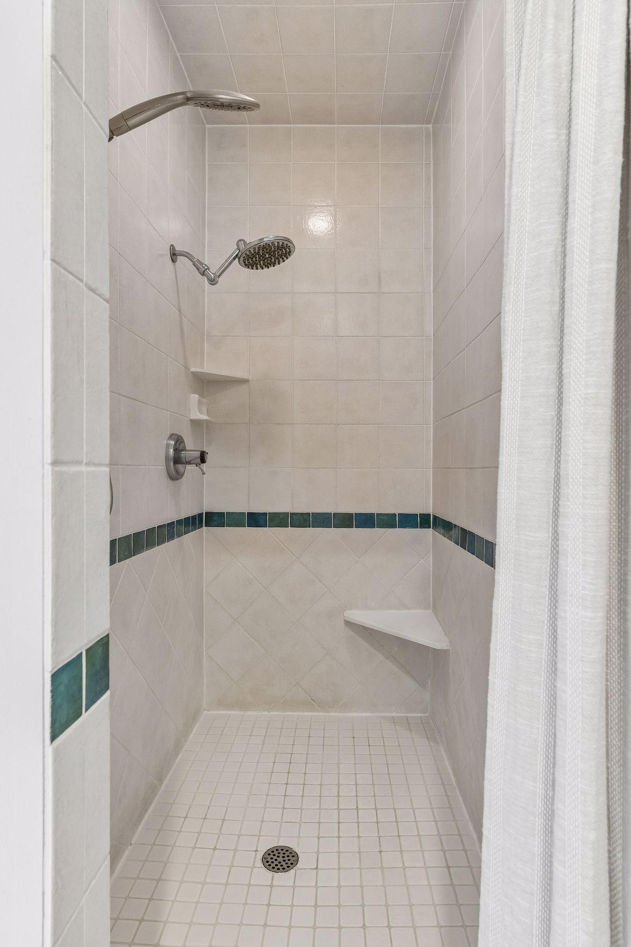 Custom tiled walk-in shower with dual shower heads.