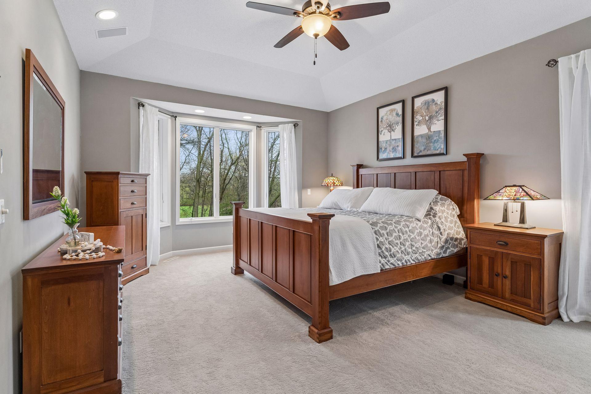 Luxurious main level primary suite with a bayed window that overlooks a lush backyard and golf course.