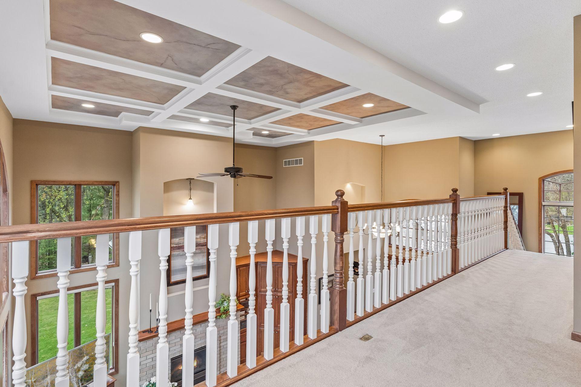 View of the rich ceiling finish in the two story great room and elegant spindles from the upper level loft.