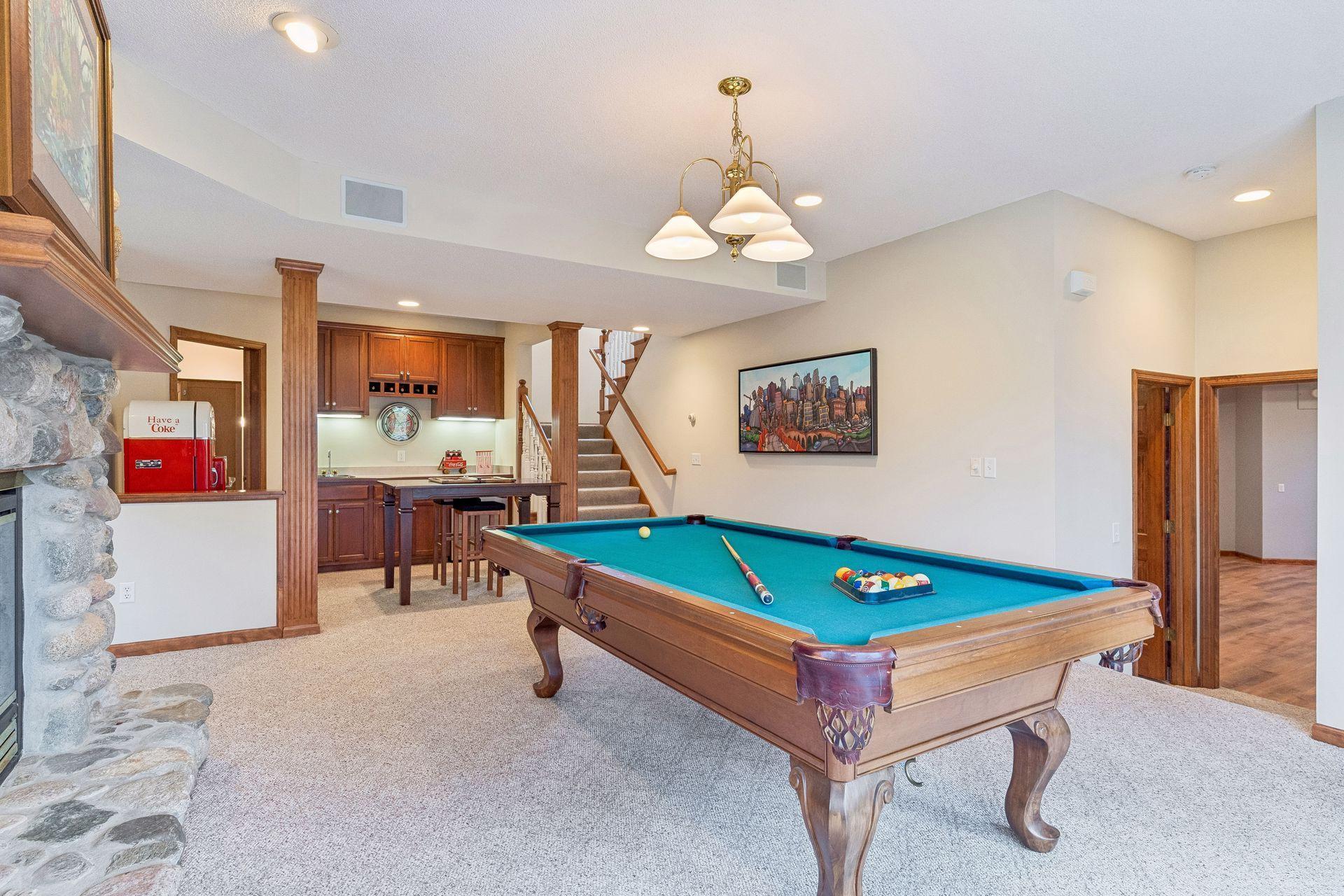 Spacious billiard area and wet bar complete with custom cabinetry and a beverage refrigerator.