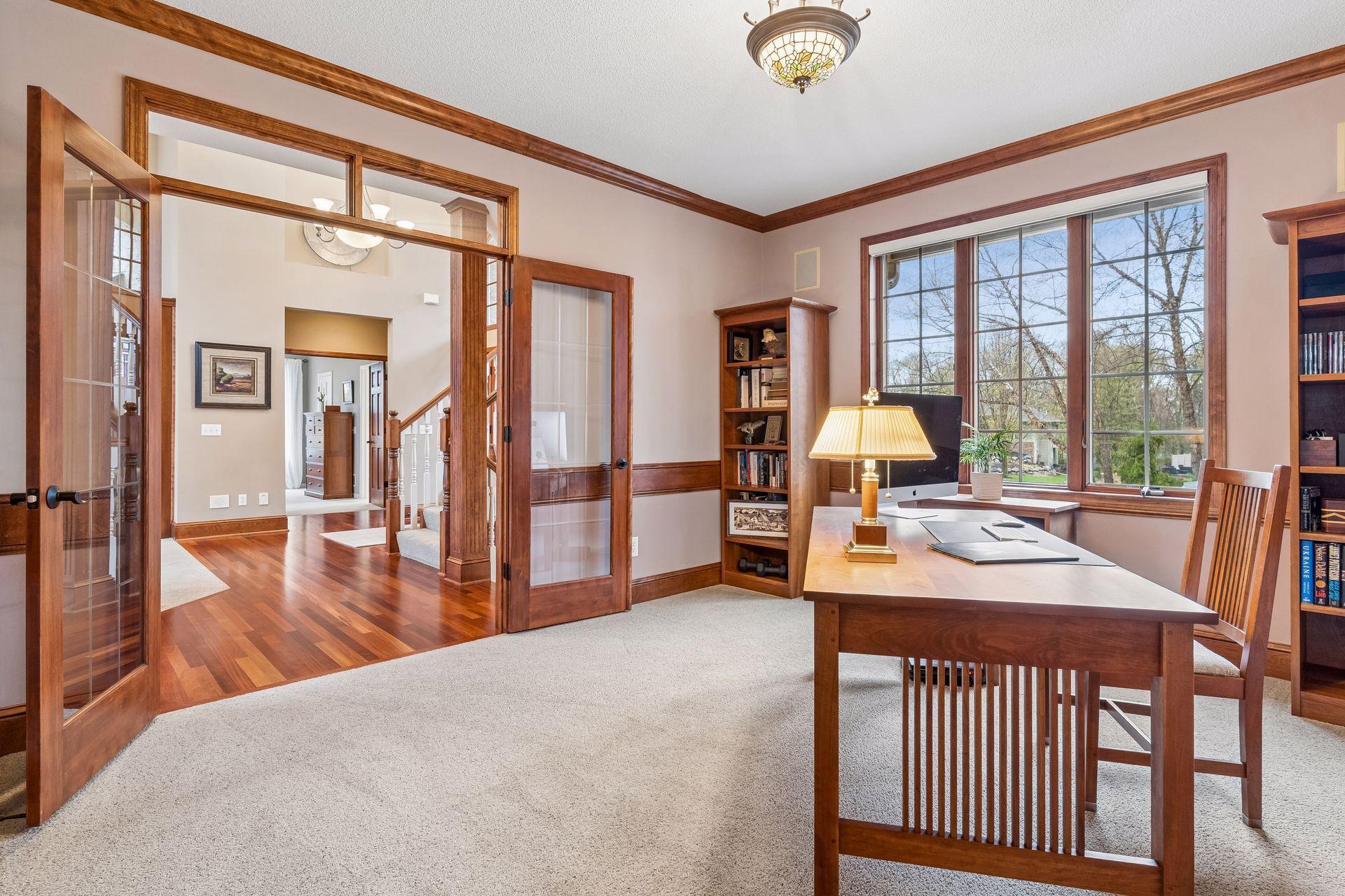 A glass French style door with a transom window above adds elegance to the main level in-home office.