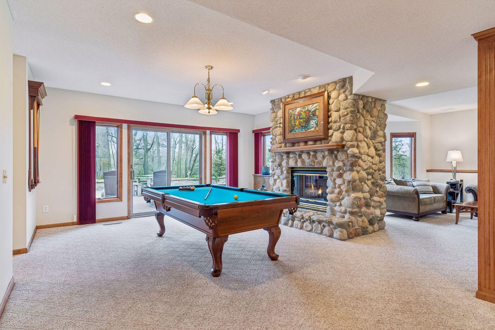 Sprawling walkout lower level family room with a rustic stone fireplace, perfect for casual entertainment.