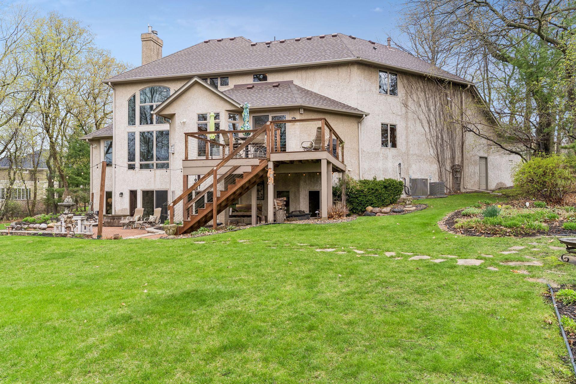 Rear view of home showing its expansive paver patio for entertaining and many perennial gardens located throughout this spectacular lot.