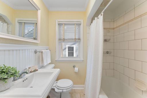 Main level full bath is bright and white.