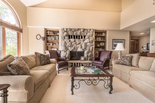 large sun drenched living room with wood fireplace and Built in cabinetry and Book Cases.