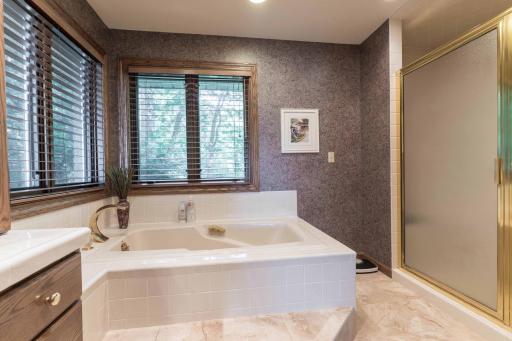 Jetted tub with separate shower tile floor and duel vanity.