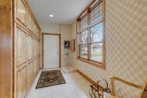 Mud room to garage has abundance of cabinets and a dog shower.