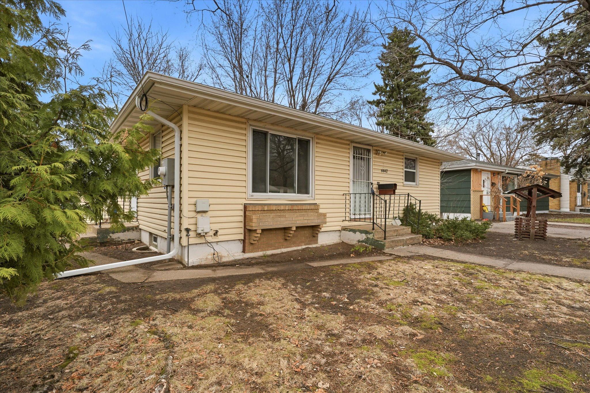 Welcoming front exterior with a concrete walkway leading to the front entry, surrounded by established landscaping and a spacious yard.
