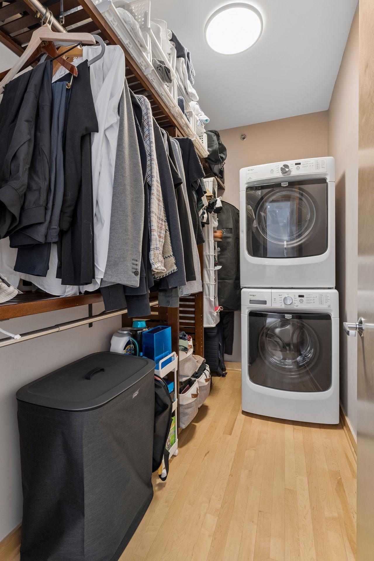 Walk-in closet with built-ins and convenient stacked full size washer and dryer.