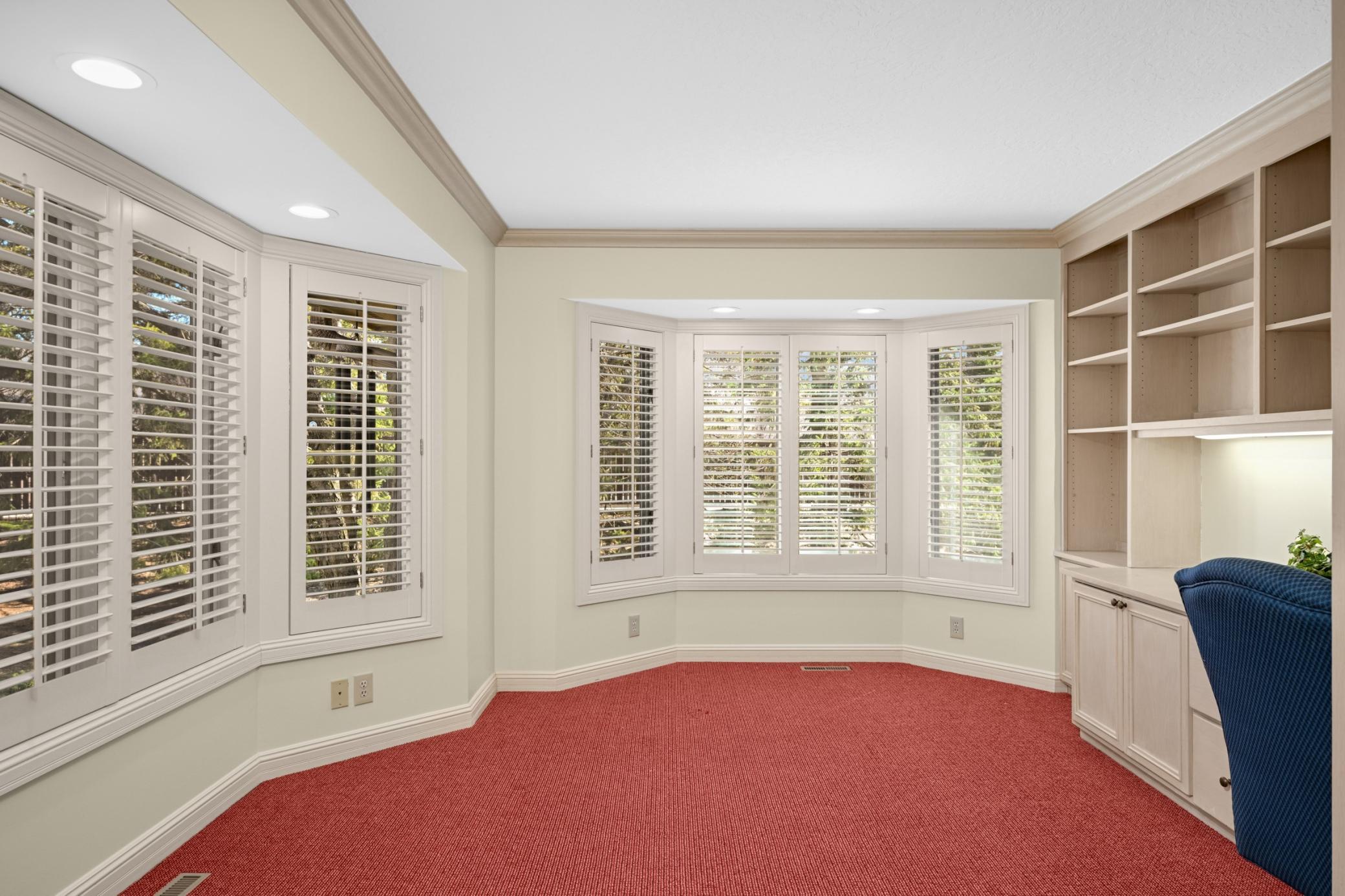 A wonderful main floor den/office features 2 bay windows with plantation shutters