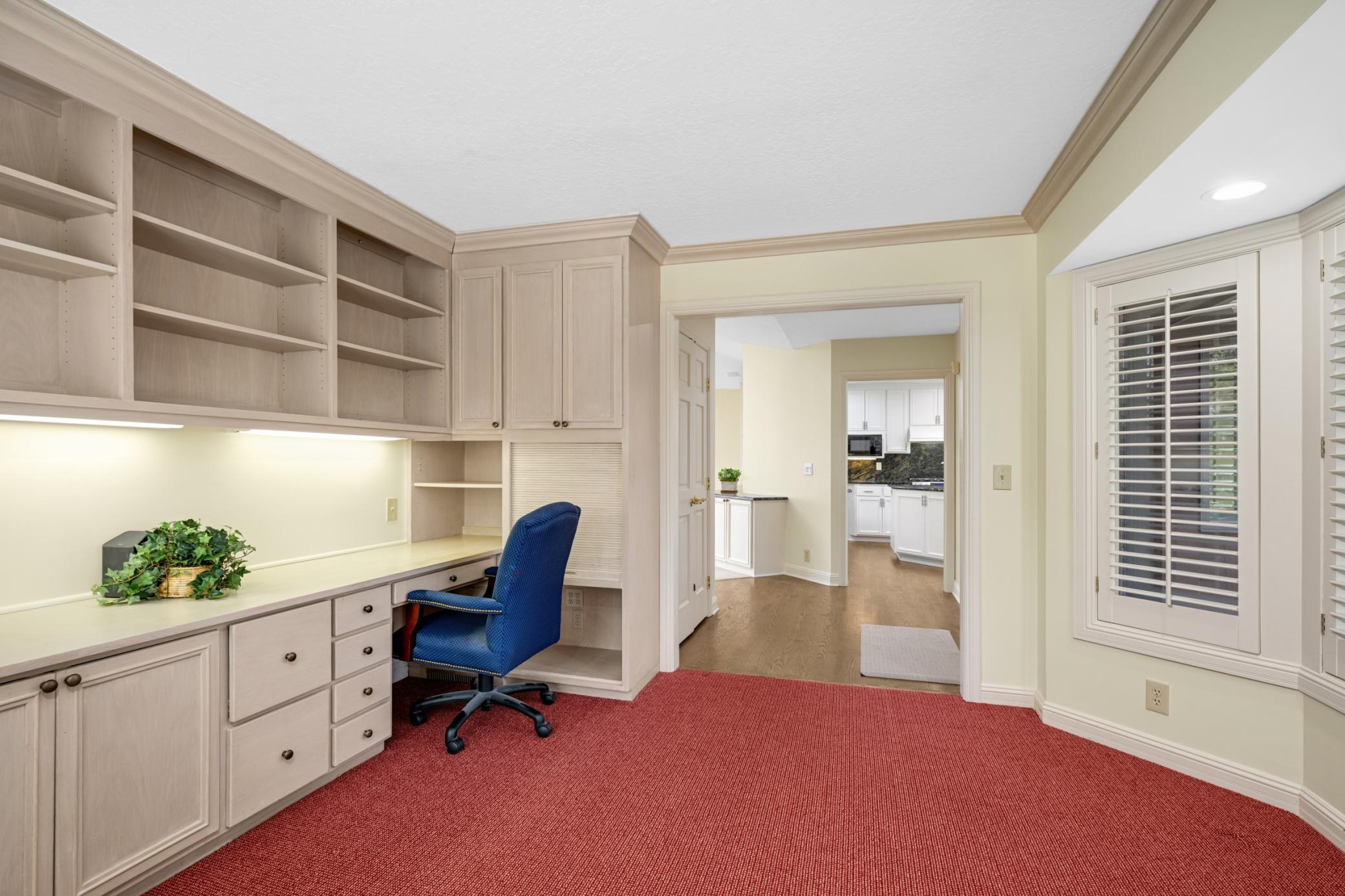 There is a wall of built-in cabinets, bookshelves and a desk