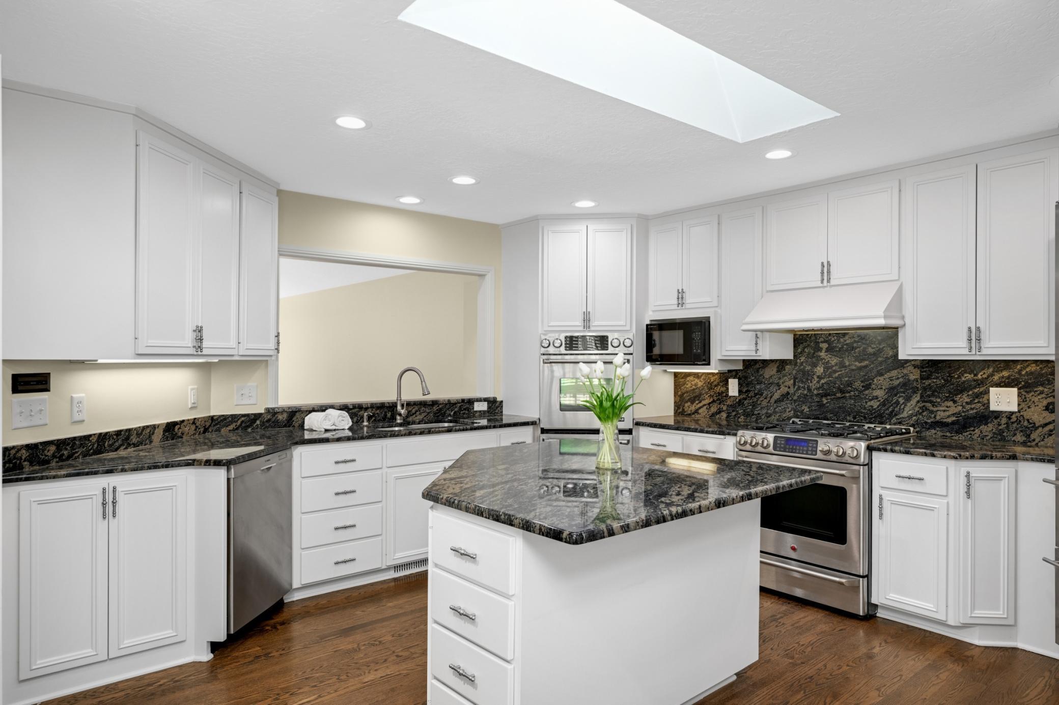 Beautiful white center island kitchen with granite countertops and stainless steel appliances.