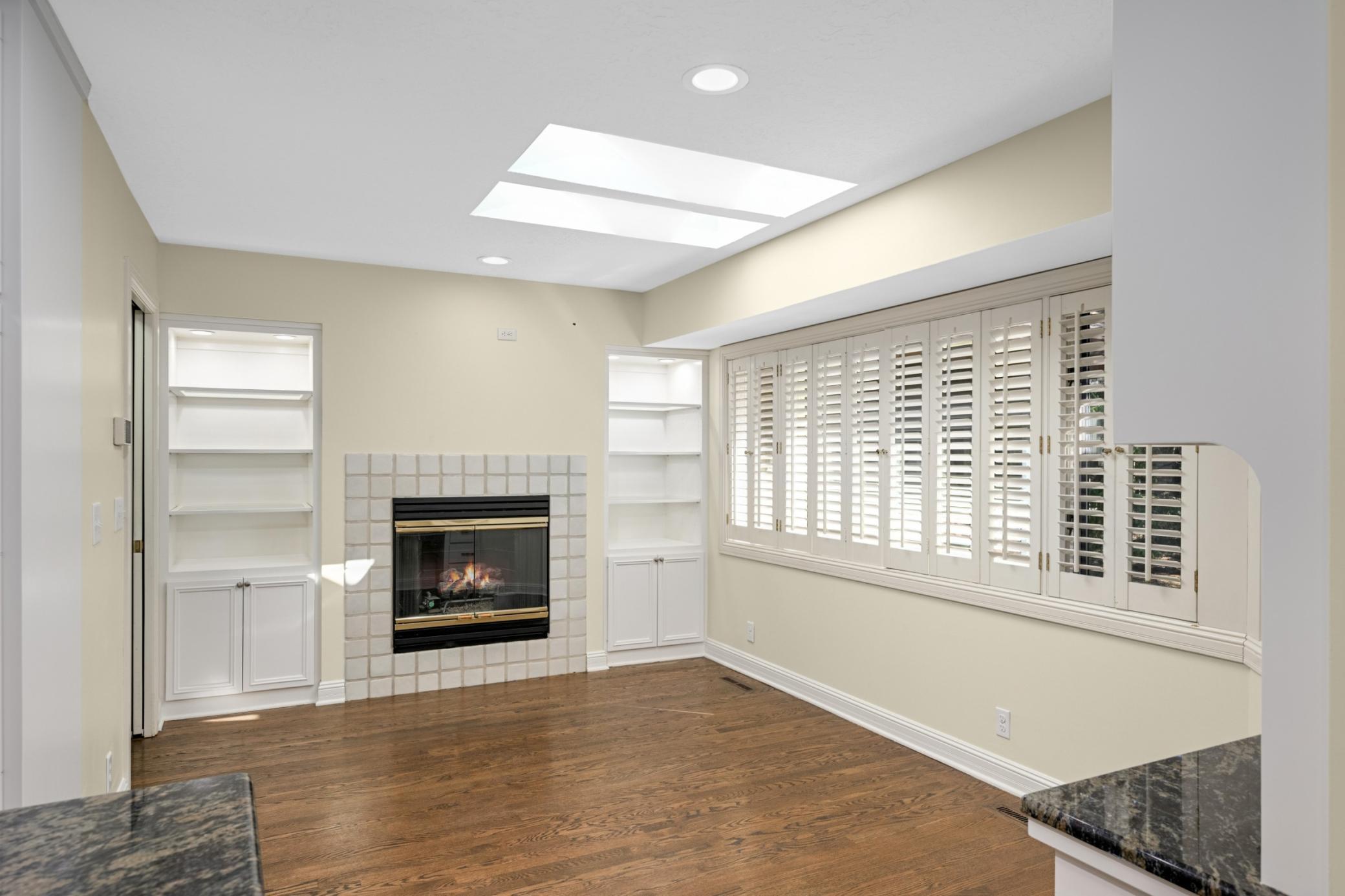 The informal dining are has newly refinished hardwood floors a huge south facing window and a gas fireplace flanked by lit display cases.