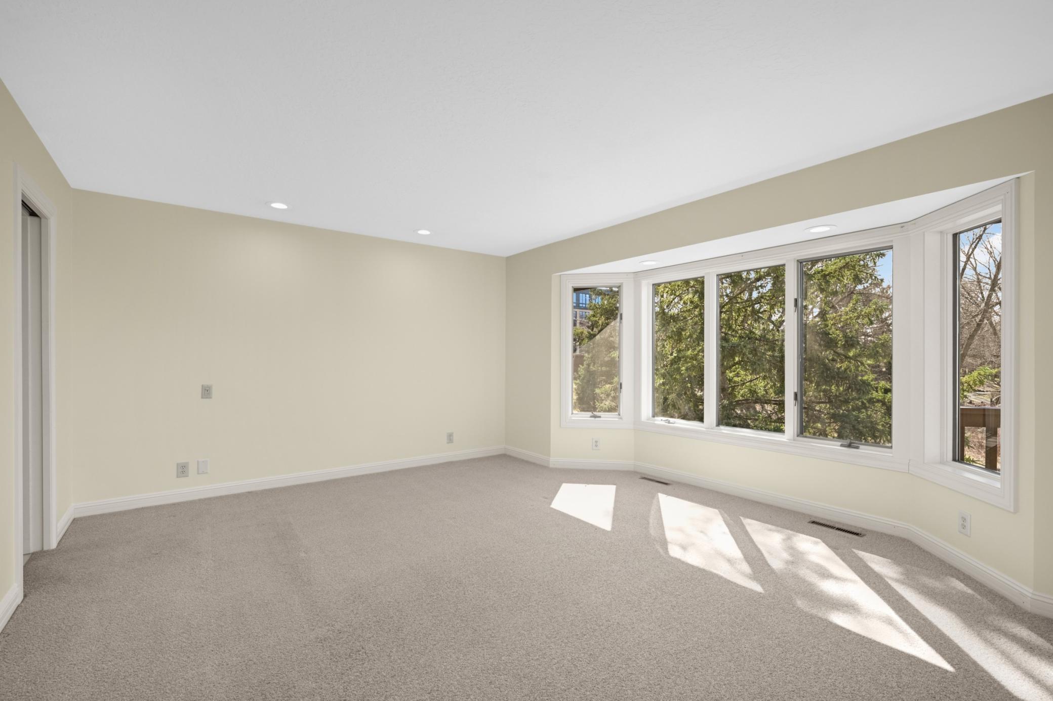 The spacious primary suite features a large bay window overlooking the pond.