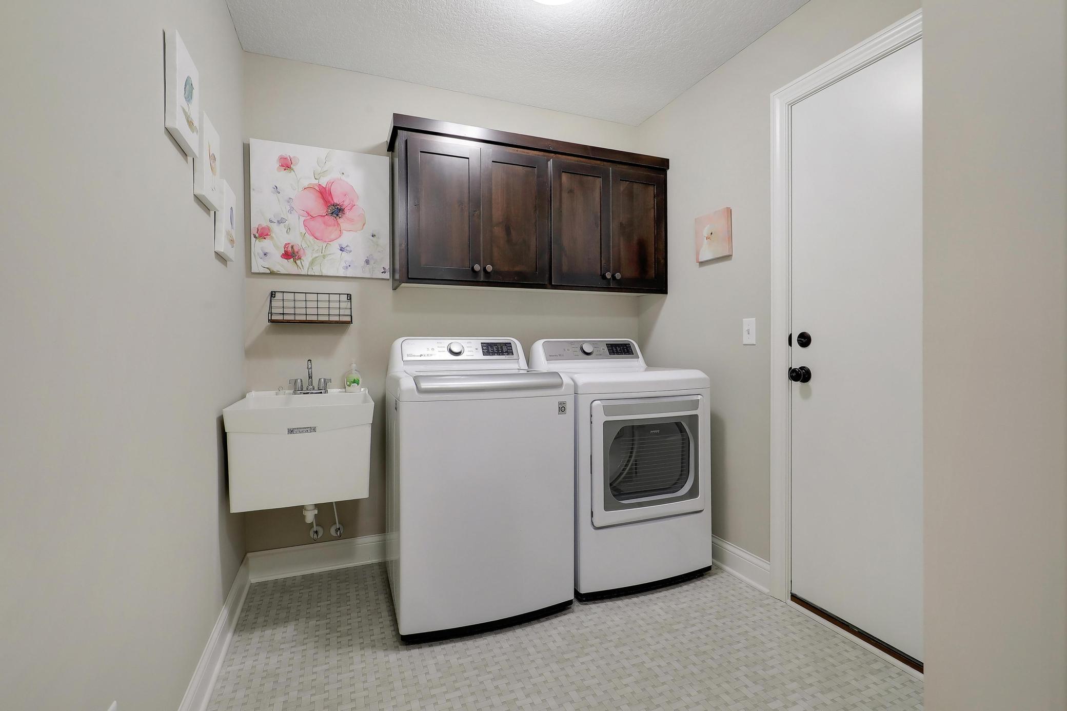 Walk thru laundry with a sink, cabinets and closet has access to the garage