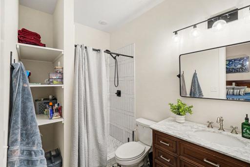 Primary bathroom has a tile-surround walk-in shower, an updated mirror and a large vanity.