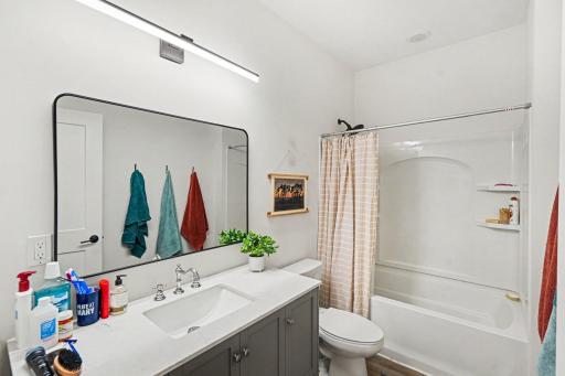 Full hall bath has a modern light and updated mirror.