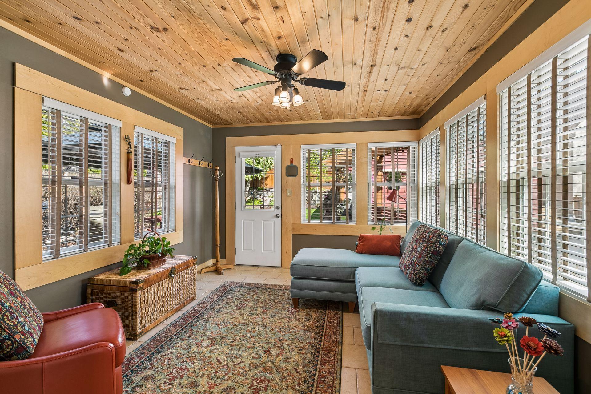 Main level den feels like a cozy cabin retreat, featuring a pine ceiling detail, heated tile flooring, and serene views of the backyard garden. Access to the back deck and garage.