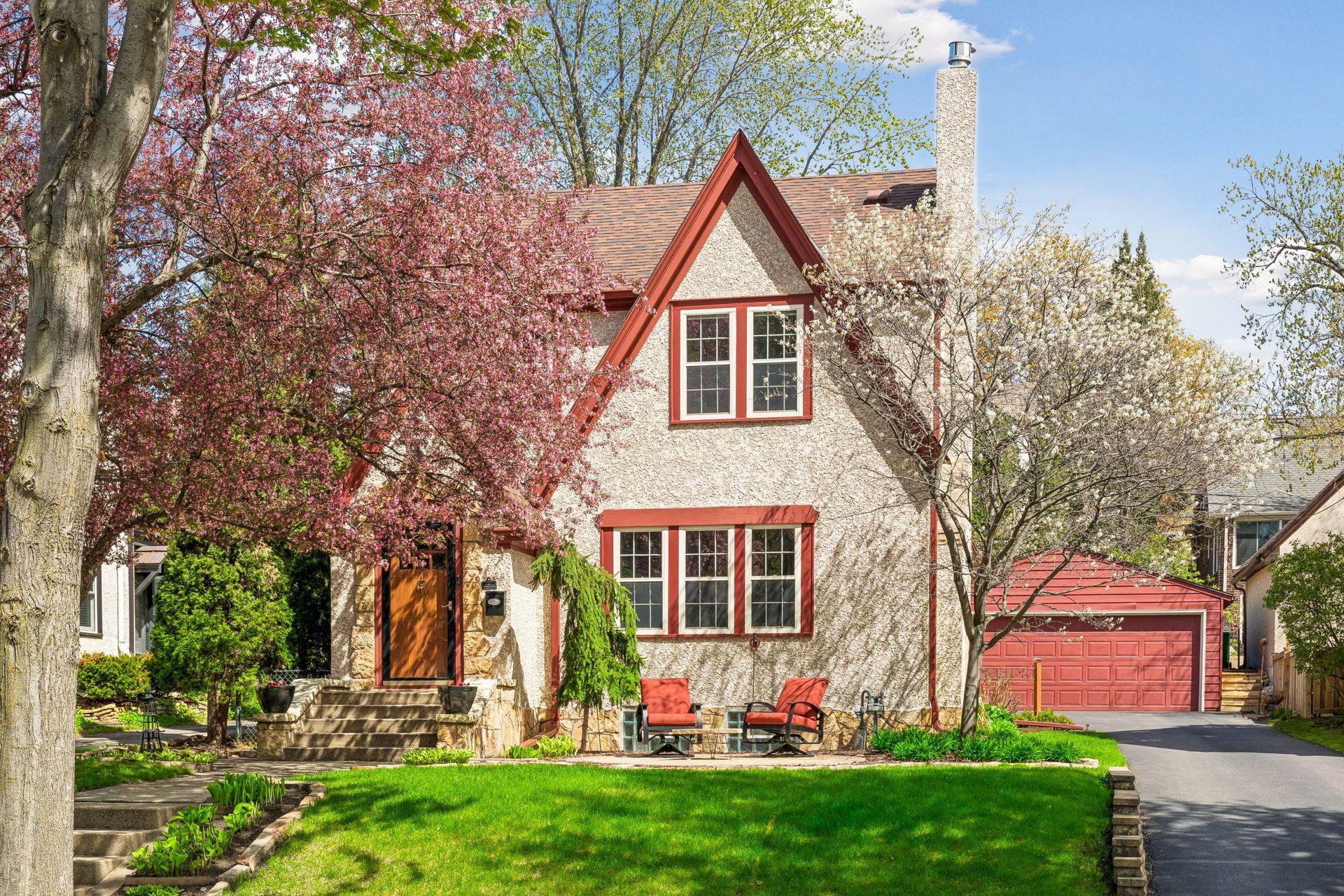 Front exterior curb appeal shines with a beautifully crafted paver patio, vibrant, lush gardens, and a perfectly placed spot to relax and enjoy the neighborhood.
