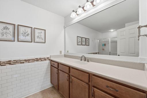 Primary ensuite features a large vanity and mirror. Tons of storage and counter space. Note the tile on the walls as well.
