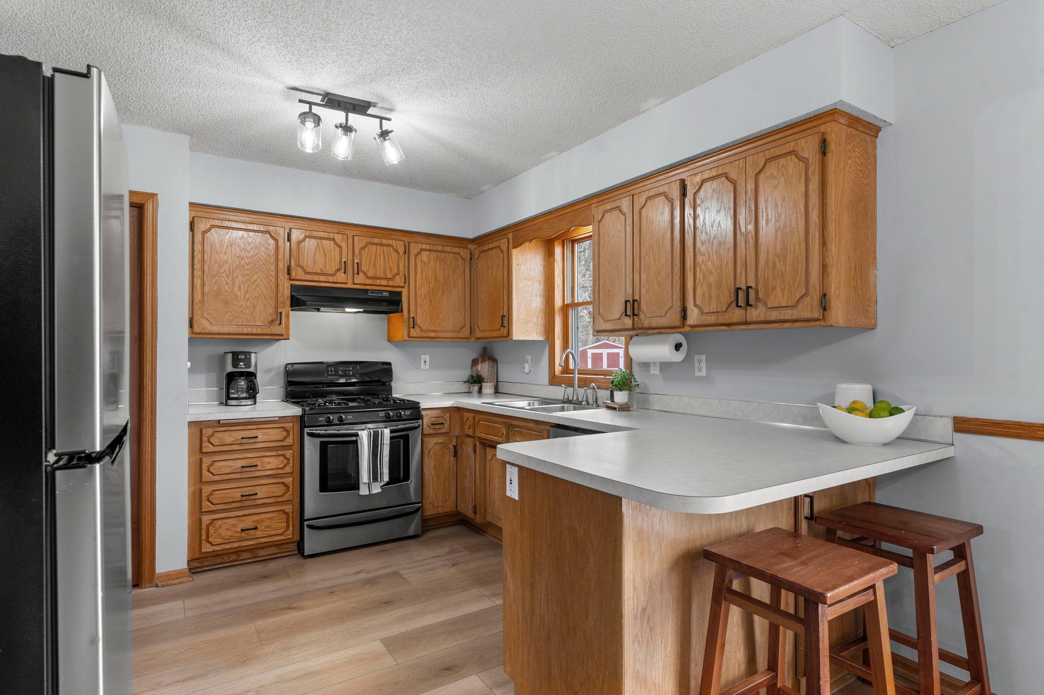 The kitchen features stainless steel appliances, ample wood cabinetry, and generous counter space.