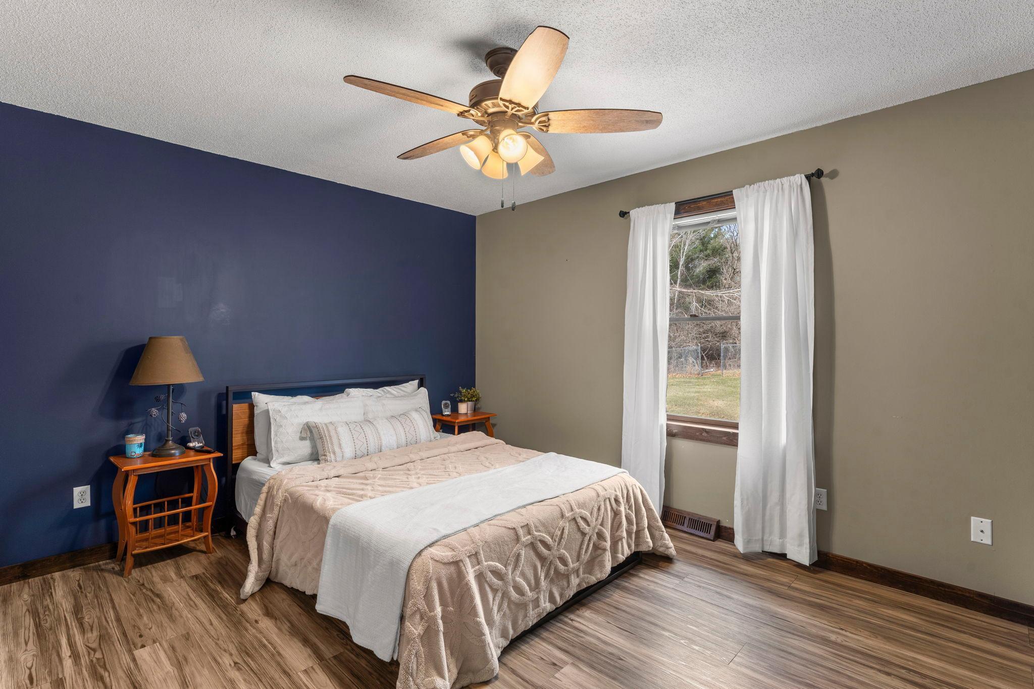 The main-floor primary bedroom features a ceiling fan, luxury plank flooring, and dual closets.